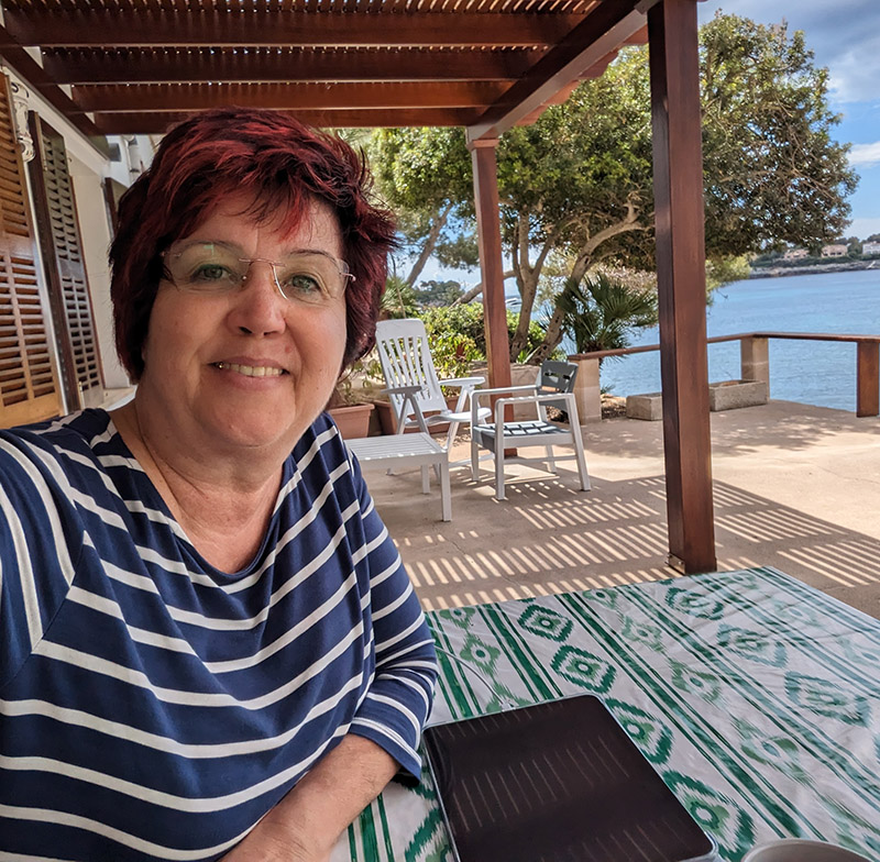 Life & Business Coach Carmen Reuter sitzt entspannt auf einer Terrasse am Meer